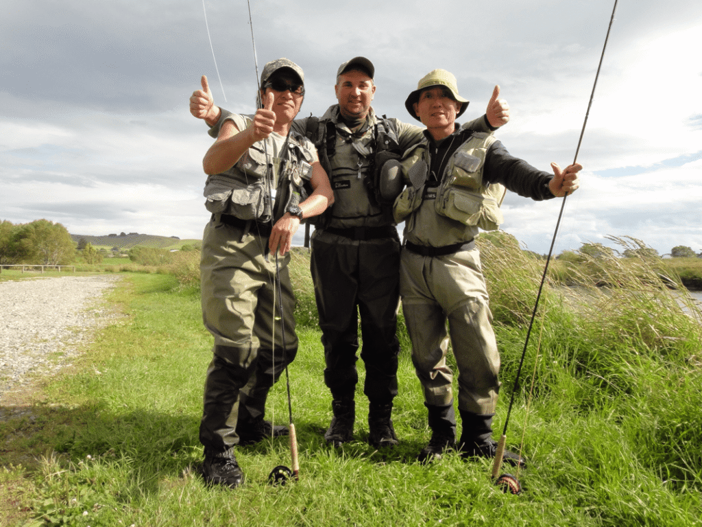 Group of fly fishing anglers giving thumbs up after a successful guided fly fishing trip on the Mataura River in New Zealand